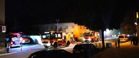 Feuerwehrfahrzeuge und Rettungskräfte sind nachts bei einem Einsatz in einer Wohnstraße aktiv.