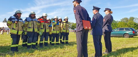 Feuerwehrleute in Uniform stehen auf einer Wiese in Allach, während sie von drei Offizieren inspiziert werden.