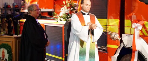 Ein Priester segnet mit Weihrauch ein neues Feuerwehrfahrzeug während einer feierlichen Zeremonie.
